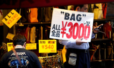 Un employé de magasin tient une pancarte pour attirer les clients à Tokyo