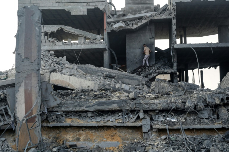 Un Palestinien se fraye un chemin dans les décombres d'un bâtiment détruit par une frappe israélienne dans le camp de réfugiés de Bureij, dans le centre de la bande de Gaza, le 10 juillet 2025 ( AFP / Eyad BABA )