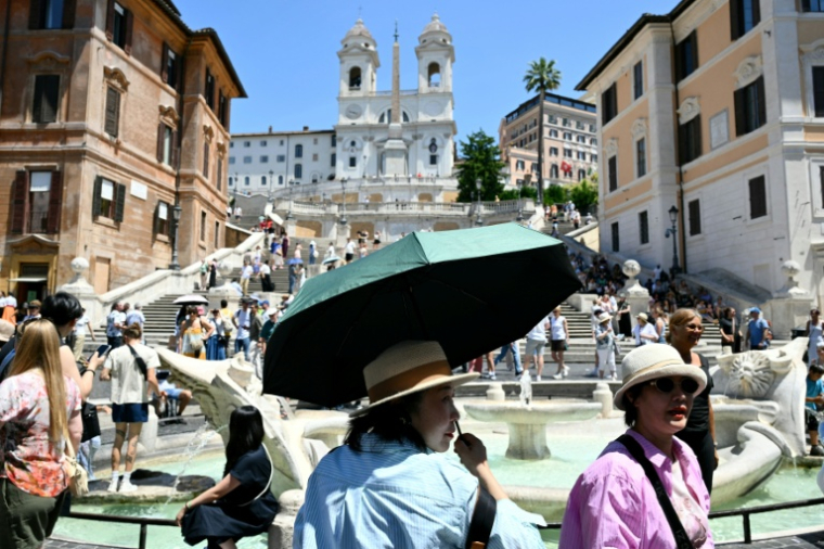 Des touristes se protègent de la chaleur avec des parapluies et des chapeaux, à Rome, le 26 mai 2026 ( AFP / Alberto PIZZOLI )
