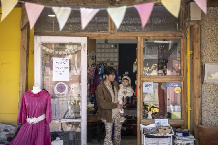 Une femme portant un enfant sort d'un magasin, à Mitzpe Ramon le 15 mars 2026 ( AFP / OLYMPIA DE MAISMONT )