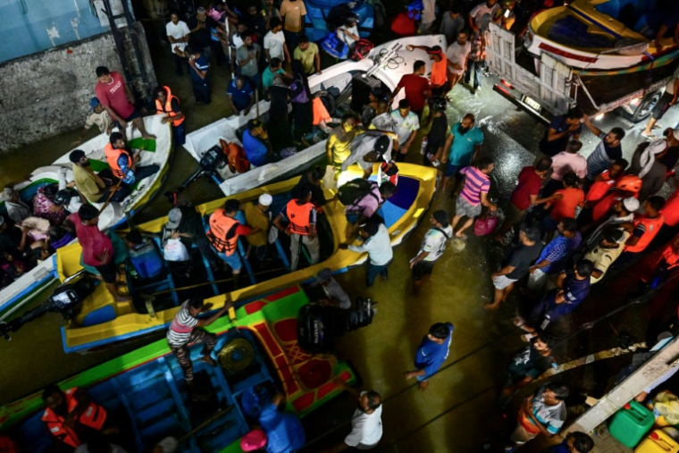 Des secouristes évacuent des habitants du village sri-lankais de  Wellampitiya, près de la capitale Colombo, avec des bateaux de  l'armée,  dans une rue inondée après de fortes pluies  le 30 novembre 2025 ( AFP / Ishara S. KODIKARA )