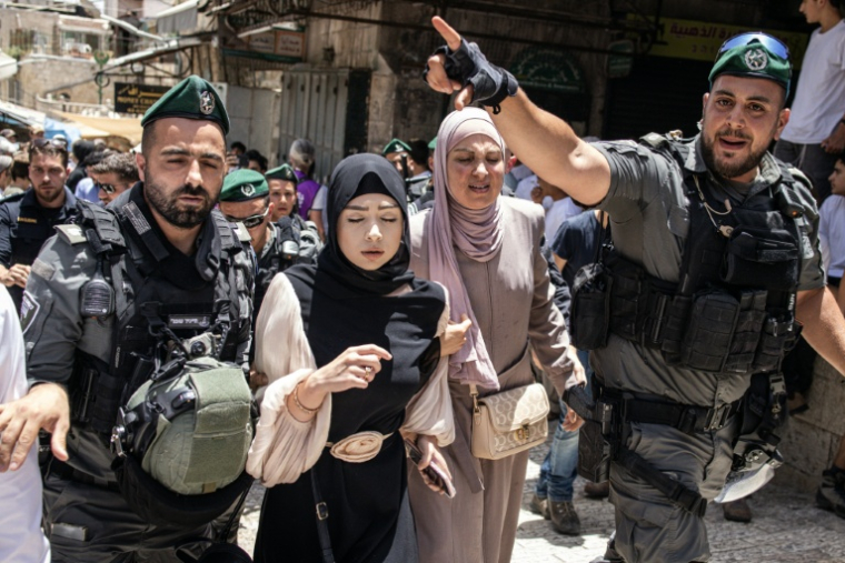 Les forces de sécurité israéliennes escortent des femmes palestiniennes qui ont été attaquées par des militants israéliens d'extrême droite dans la vieille ville de Jérusalem, le 26 mai 2025. ( AFP / John Wessels )