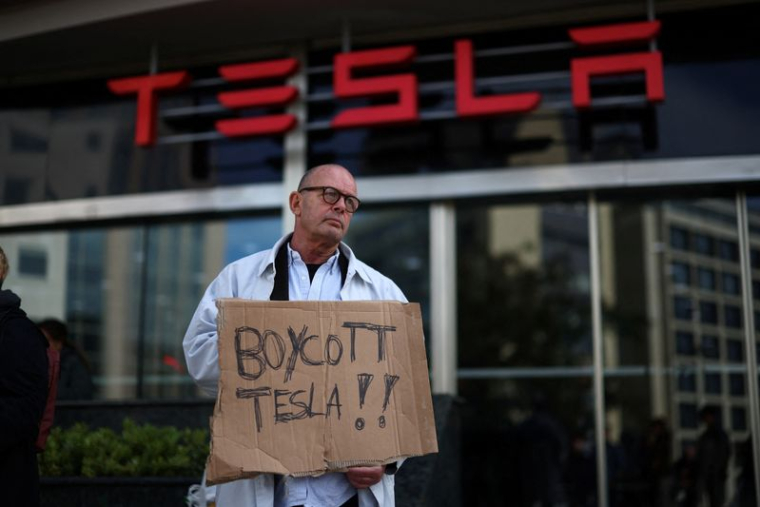 Une personne manifeste contre Tesla et Elon Musk devant une concession Tesla à Lisbonne