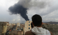 Un journaliste prend une photo de la fumée noire qui s'élève après une frappe israélienne sur Sanaa, la capitale du Yémen tenue par les rebelles houthis, le 24 août 2025 ( AFP / Mohammed HUWAIS )