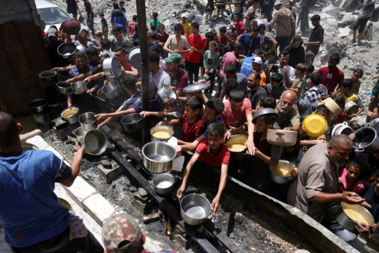 Des déplacés palestiniens se rassemblent pour collecter des repas gratuits auprès d'une association caritative à Jabalia, dans le nord de la bande de Gaza, le 19 mai 2025 ( AFP / Bashar TALEB )