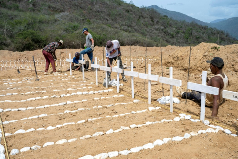 Des personnes mettent en ordre des tombes de victimes non-identifiées du double séisme au Venezuela, le 5 juillet 2026 à Catia La Mar, dans l'Etat de La Guaira ( AFP / Miguel MEDINA )