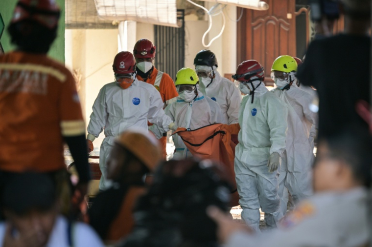 Des membres des équipes de secours transportent un sac mortuaire sur le site de l'effondrement de l'internat islamique Al Khoziny à Sidoarjo, dans l'est de Java, le 6 octobre 2025 en Indonésie ( AFP / JUNI KRISWANTO )