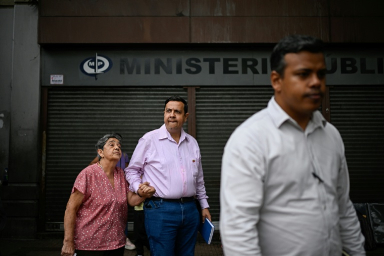 Le défenseur des droits humains Javier Tarazona tient la main de sa mère, Teresa Sanchez, devant un tribunal après le report de son audience à Caracas, le 14 avril 2026 ( AFP / Federico PARRA )