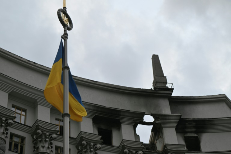 Un drapeau ukrainien flotte devant le bâtiment du gouvernement ukrainien endommagé la veille lors d'une frappe aérienne massive russe, le 8 septembre 2025 à Kiev  ( AFP / Genya SAVILOV )