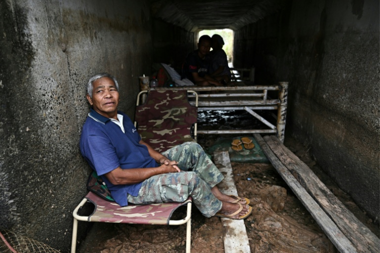 Le fermier thaïlandais Boonkerd Yudeerum est assis dans un bunker avec sa famille dans la province de Surin le 10 décembre 2025, lors d'affrontements le long de la frontière thaïlando-cambodgienne ( AFP / Lillian SUWANRUMPHA )