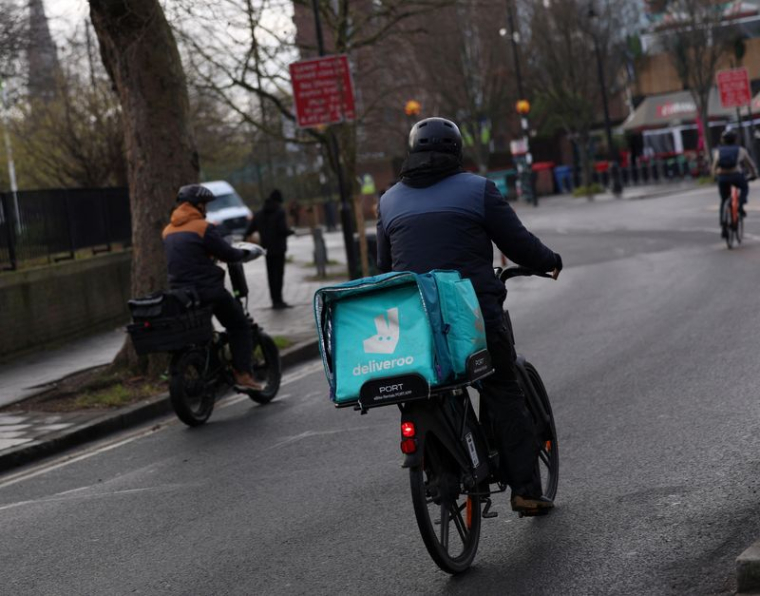 Un livreur portant un sac à dos Deliveroo circule à vélo à Londres