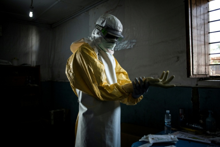 Un personnel de santé enfile son équipement de protection avant d'entrer dans la zone rouge d'un centre de traitement Ebola (CTE) soutenu par MSF, le 6 novembre 2018 à Bunia, en RDC ( AFP / John WESSELS )