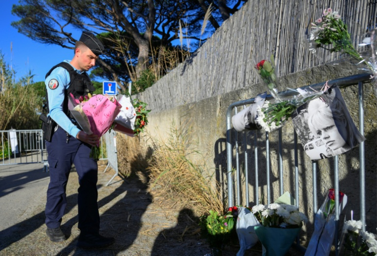 Un gendarme dépose des fleurs devant une barrière en hommage à Brigitte Bardot à l'entrée de sa propriété de Saint-Tropez, le 28 décembre 2025 ( AFP / Frederic DIDES )