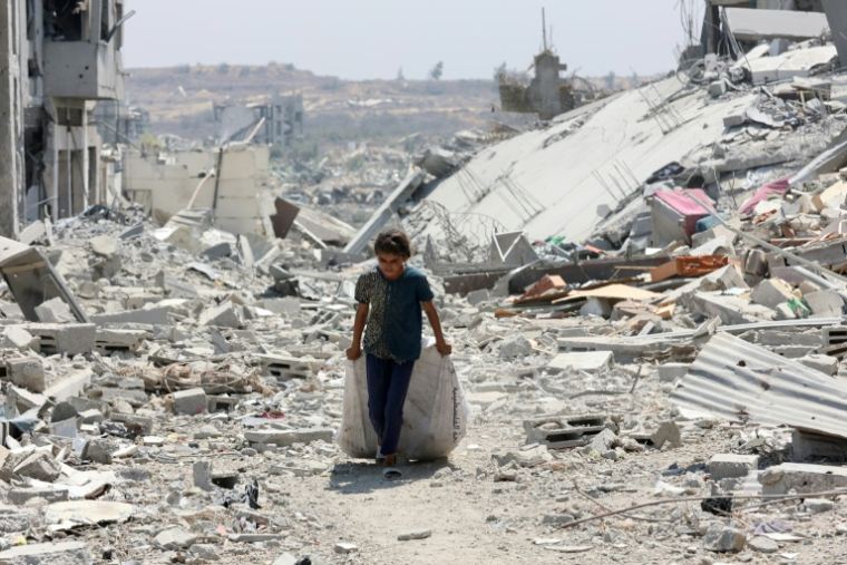 Une fillette palestinienne transporte des affaires qu'elle a pu sauvées, au milieu des destructions dans le quartier al-Touffah de la ville de Gaza, le 14 août 2025 ( AFP / Omar AL-QATTAA )