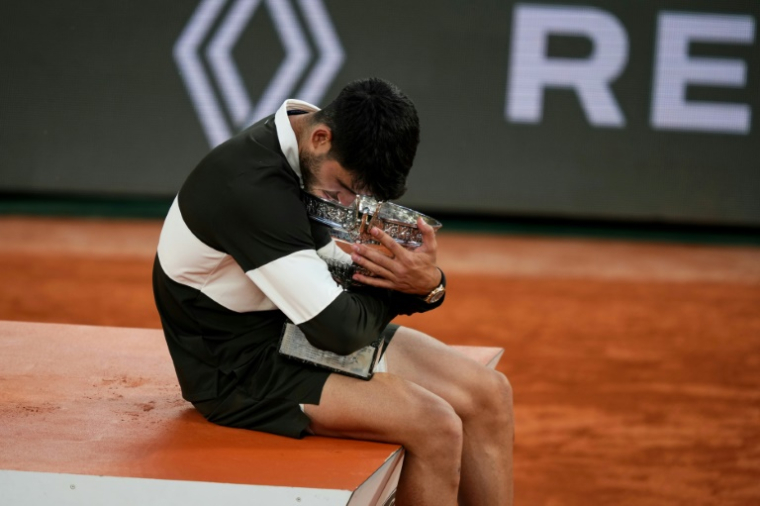L'Espagnol Carlos Alcaraz enlace le trophée de Roland-Garros après sa victoire en finale sur l'Italien Jannik Sinner, le 8 juin 2025 à Paris ( AFP / Dimitar DILKOFF )