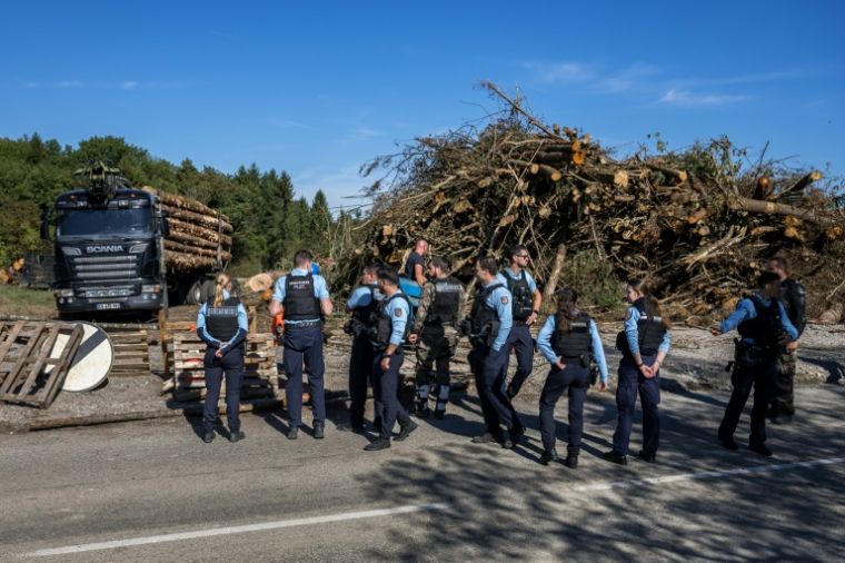 Des policiers le long d’une route, après que des manifestants ont bloqué un camion transportant des grumes dans le cadre de la construction controversée de l’autoroute A412, près de Perrignier, en Haute-Savoie, le 14 octobre 2026 ( AFP / Fabrice COFFRINI )