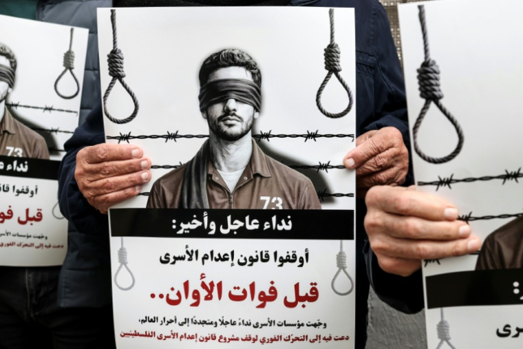 Des manifestants brandissent des pancartes sur lesquelles on peut lire "Appel urgent et final : arrêtez l'application de la loi sur les prisonniers avant qu'il ne soit trop tard" devant les locaux de la Croix-Rouge à Ramallah, en Cisjordanie occupée par Israël, le 31 mars 2026 ( AFP / Zain JAAFAR )