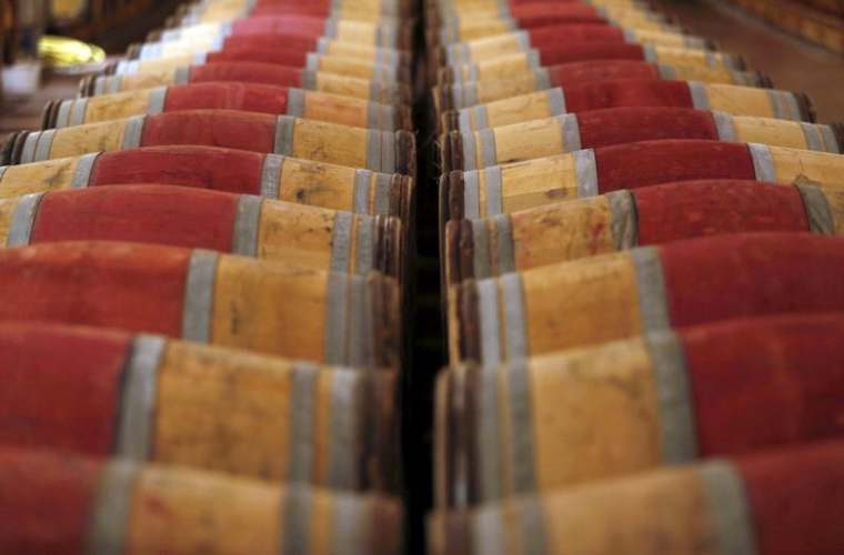 Photo de tonneaux de vin rouge stockés dans la cave du Château Domaine de Chevalier à Léognan, près de Bordeaux
