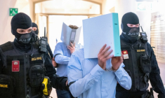 Des prévenus cachent leurs visages derrière un dossier, escortés par des policiers vers la salle d'audience du tribunal de Wiener Neustadt, le 28 mai 2026 en Atriche, lors du procès pour un complot contre un concert de la star américaine Taylor Swift à Vienne ( AFP / Joe Klamar )