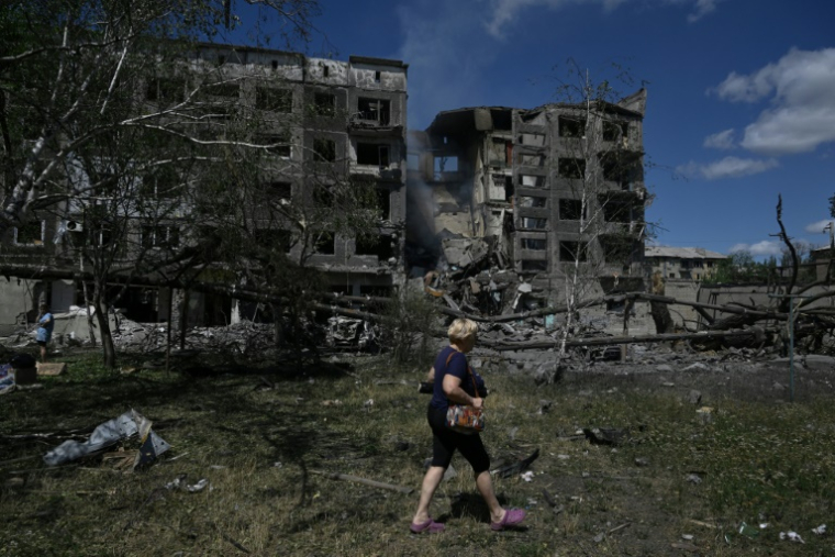 Une femme marche à Bilozerske, près de bâtiment bombardés par la Russie, le 12 août 2025 ( AFP / Genya SAVILOV )