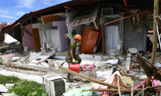 Un sauveteur arrive devant un  bâtiment effondré où la disparition de trois personnes a été signalée après un séisme, dans la ville de Bogo, aux Philippines, le 1er octobre 2025 ( AFP / TED ALJIBE )