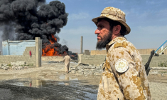 Un membre des forces de sécurité talibanes monte la garde alors que de la fumée s'élève du site de frappes aériennes pakistanaises sur des dépôts pétroliers, près de l'aéroport de Kandahar, le 13 mars 2026 en Afghanistan ( AFP / STR )