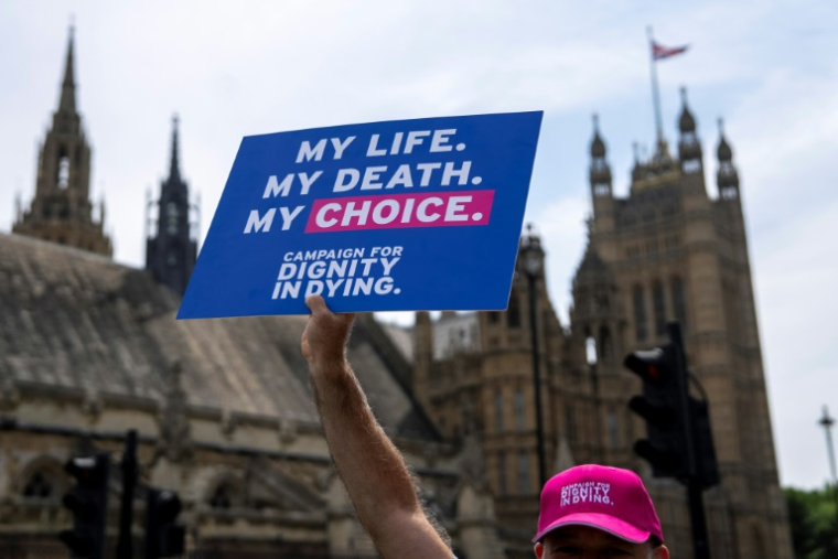 Un militant pour une modification de la loi sur l'aide médicale à mourir tient une pancarte devant le Palais de Westminster, le 20 juin 2025 à Londres, alors que les députés doivent voter sur l'opportunité d'autoriser l'aide à mourir pour certains malades en phase terminale ( AFP / CARLOS JASSO )