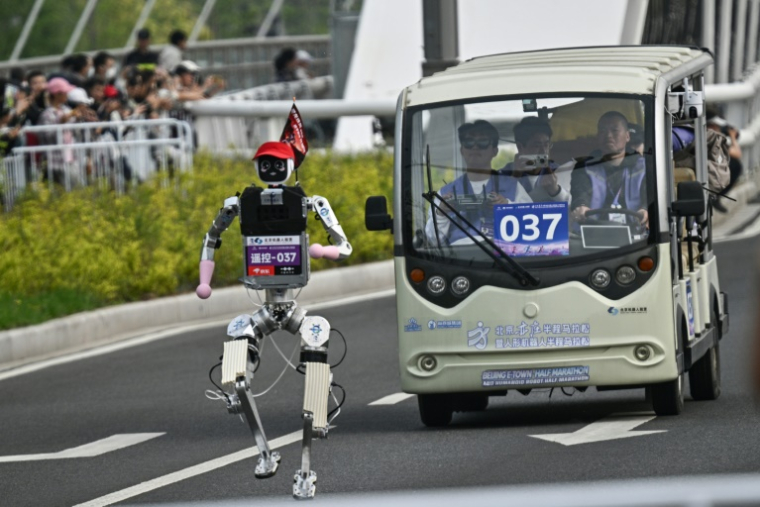 Un robot suivi par une équipe d'ingénieurs, lors du semi-marathon de Yizhuang, dans la banlieue de Pékin, le 19 avril 2026 ( AFP / Pedro PARDO )