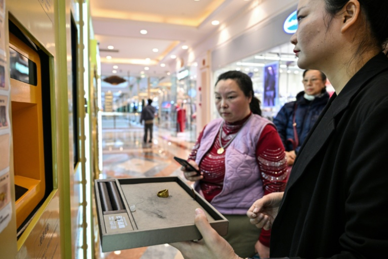 Une employée aide une cliente à vendre un bijou en or dans un automate de Shanghai, en Chine, le 29 janvier 2026 ( AFP / Hector RETAMAL )