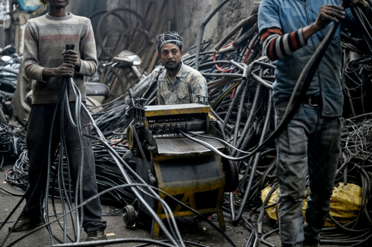 Des hommes récupérant de l'aluminium de fils plastiques dans un centre informel de recyclage de Seelampur, à New Delhi en Inde, le 28 janvier 2026 ( AFP / Arun SANKAR )