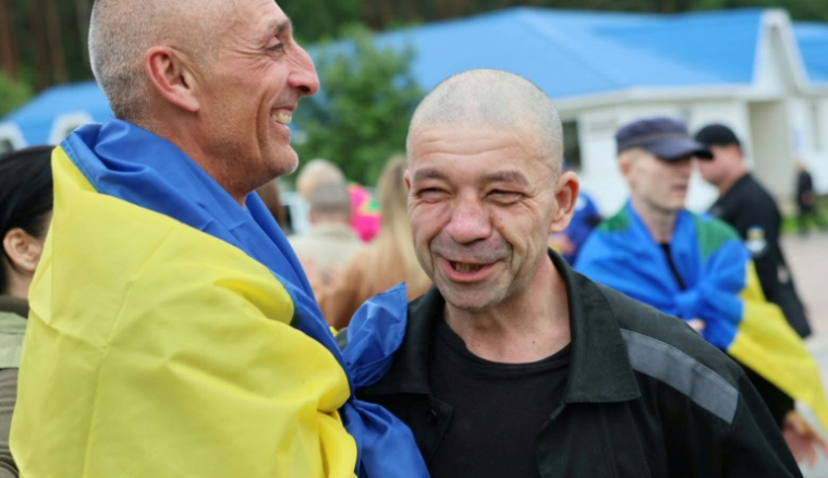Photo publiée par le quartier général de coordination pour le traitement des prisonniers de guerre, le 20 juin 2025, de prisonniers de guerre ukrainiens enveloppés dans un drapeau national à la suite d'un échange dans un lieu non divulgué en Ukraine ( Quartier général de coordination pour le traitement des prisonniers de guerre / Handout )