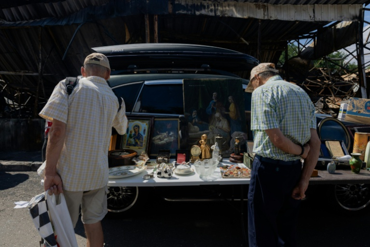 Des visiteurs regardent un étal du marché aux puces de Potchaiïna à Kiev, endommagé par une  une frappe russe, le 9 août 2026 à Kiev, en Ukraine ( AFP / Tetiana DZHAFAROVA )