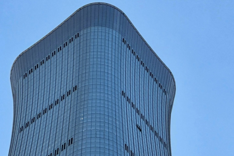 Un trou (d) sur la façade de la tour CITIC à Pékin, après que des témoins ont signalé la présence de débris d'avion au pied du plus haut bâtiment de la ville, le 26 juin 2026 en Chine  ( AFP / Peter CATTERALL )