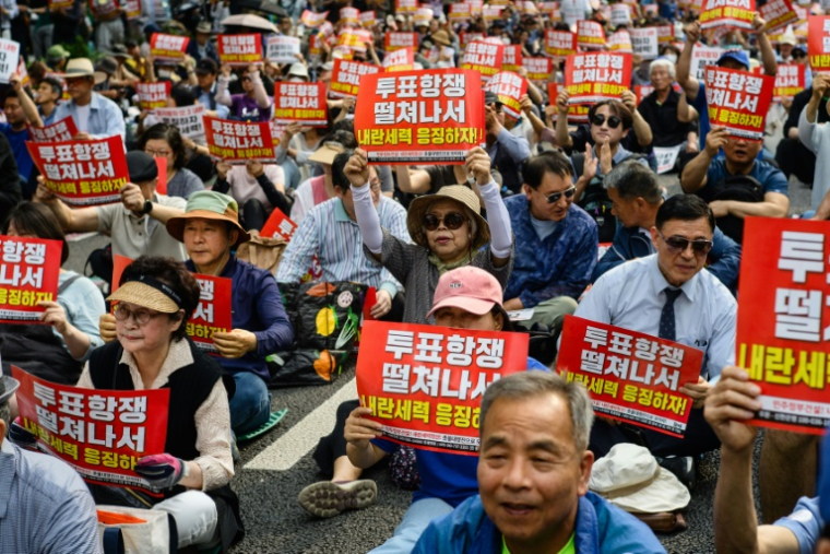 Des manifestants brandissent des pancartes "N'oublions pas l'insurrection du 3 décembre. Punissons les forces insurrectionnelles" lors d'un rassemblement à Seocho, dans le sud de Séoul, le 31 mai 2025, avant l'élection présidentielle du 3 juin ( AFP / ANTHONY WALLACE )