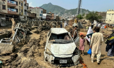 Des habitants de Mingora sont réunis autour d'un véhicule endommagé et de débris après l'effondrement de la route suite aux crues subites dans la province montagneuse de Khyber Pakhtunkhwa au Pakistan le 16 août 2025 ( AFP / Mehboob UL HAQ )
