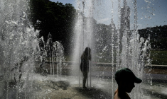 Des enfantts se rafraîchissent sous les jets d'eau d'une fontaine à Lyon, le 25 juin 2025  ( AFP / JEFF PACHOUD )