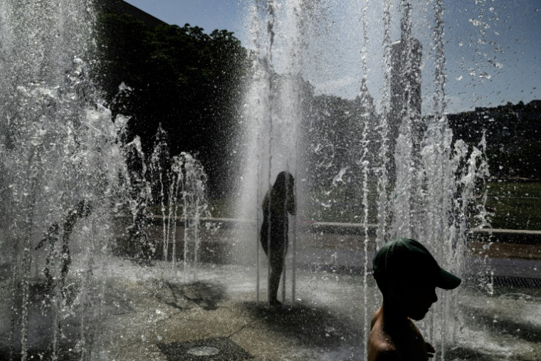 Des enfantts se rafraîchissent sous les jets d'eau d'une fontaine à Lyon, le 25 juin 2025 ( AFP / JEFF PACHOUD )
