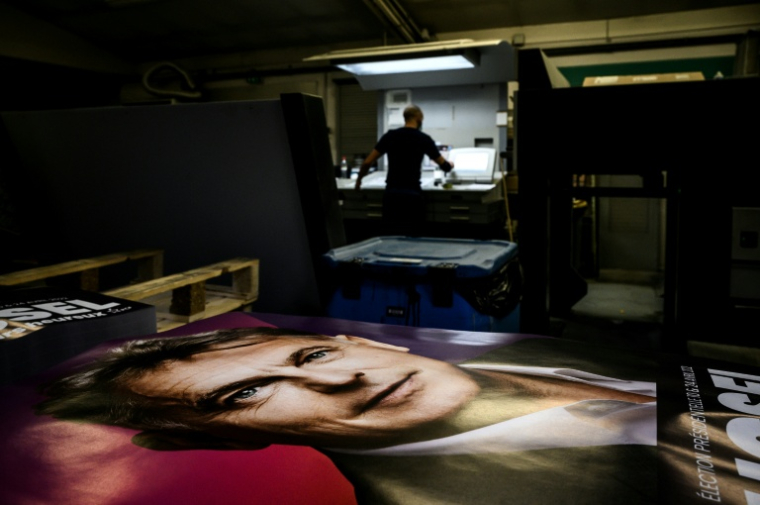 Un employé vérifie un poster de campagne électorale de Fabien Roussel, alors candidat du PCF à l'élection présidentielle, le 21 janvier 2022 à Vénissieux, dans le Rhône ( AFP / JEFF PACHOUD )