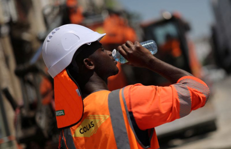 Un travailleur boit de l'eau sur un chantier de construction, lors d'une journée chaude et ensoleillée à Nantes