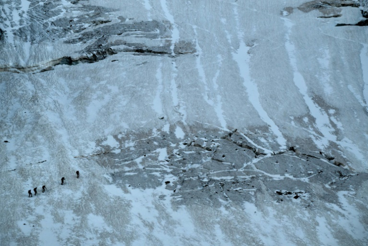 Des alpinistes marchent le long des crevasses du glacier de la Selle dans le massif des Écrins, tôt le matin, le 9 juillet 2025 à Saint-Christophe-en-Oisans, en Isère ( AFP / JEFF PACHOUD )