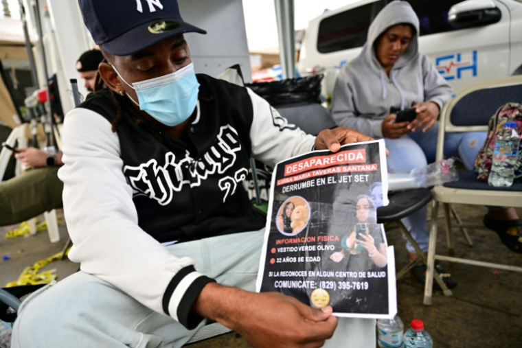 Un homme montre une photo d'une proche dont il attend des nouvelles à l'extérieur de la discothèque dont le toit s'est effondré deux jours auparavant à Saint-Domingue, le 10 avril 2025 en République dominicaine ( AFP / MARTIN BERNETTI )