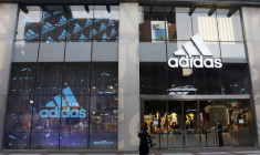 Une femme passe devant un magasin d'Adidas dans un centre commercial de Pékin