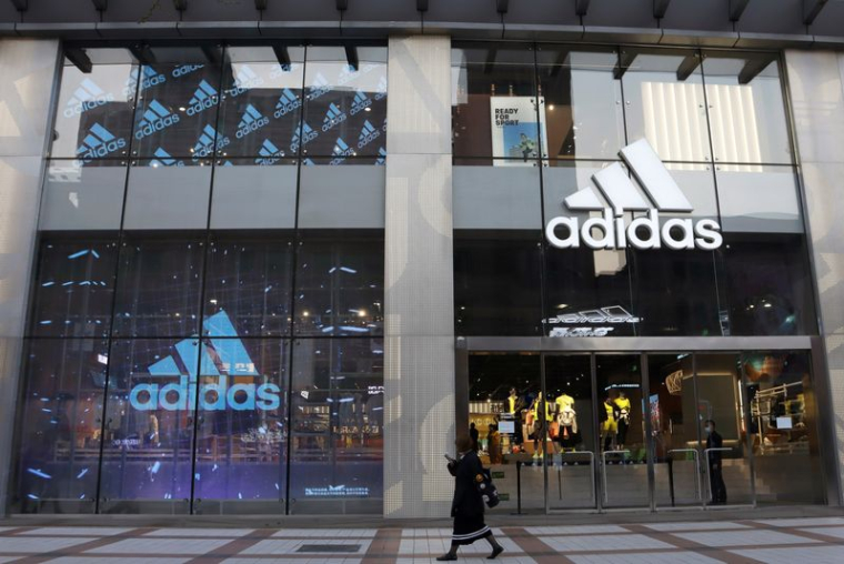 Une femme passe devant un magasin d'Adidas dans un centre commercial de Pékin