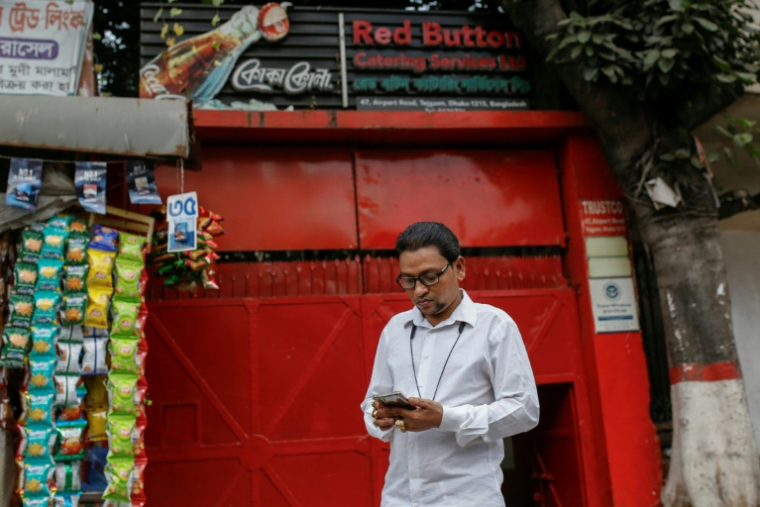 Prince Mamun, poissonnier,  qui consomme des produits de la distillerie Carew and Co. depuis vingt ans, se tient devant l'entrée d'un bar à Dacca, le 29 octobre 2025 au Bangladesh  ( AFP / Rehman ASAD )