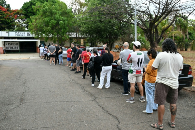 Des électeurs attendent l'ouverture des bureaux pour le premier tour de la présidentielle au Brésil à Cidade Estrutural, en périphérie de Brasilia, le 4 octobre 2026  ( AFP / Evaristo SA )