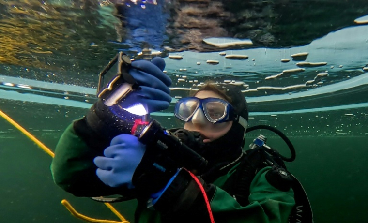 Un plongeur participe à un stage scientifique de plongée polaire, le 14 mars 2026 dans le lac de Kilpisjärvi, à l'extrême nord-ouest de la Finlande ( AFP / -STR )