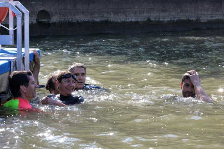 La maire de Paris Anne Hidalgo (g) et Tony Estanguet (d), membre du Comité d'organisation des Jeux paralympiques (Cojo), nagent dans la Seine, à Paris, le 17 juillet 2024, pour démontrer que le fleuve est suffisamment propre pour accueillir les épreuves de natation en plein air des Jeux olympiques de Paris ( POOL / JOEL SAGET )