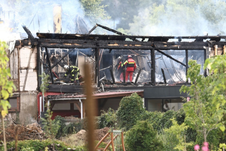 Des pompiers inspectent un bâtiment ravagé par les flammes dans un gîte pour personnes handicapées à Wintzenheim, dans le Haut-Rhin, le 9 août 2023 ( AFP / Sebastien BOZON )