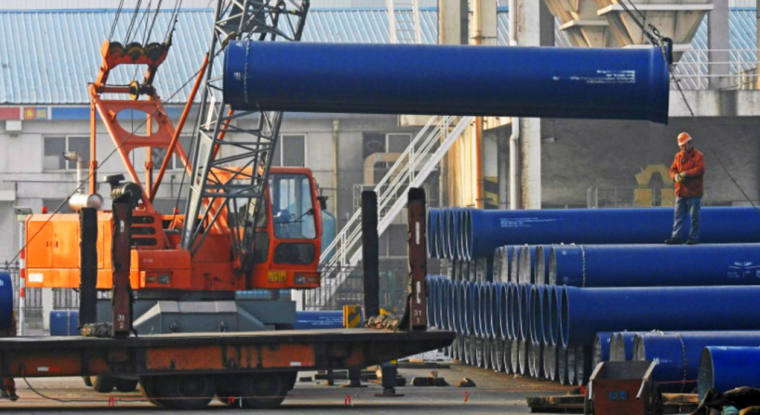Des ouvriers chargent des tuyaux en acier le 1er janvier 2017 dans le port de Lianyungang. (© STR / AFP)