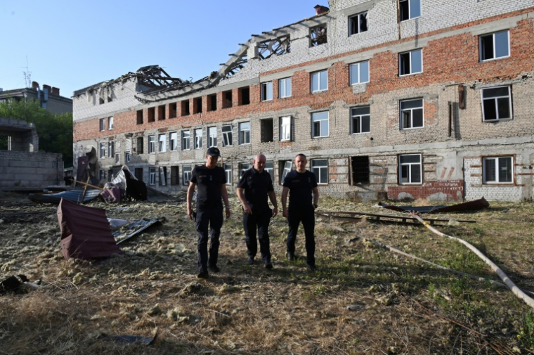 Des secouristes devant un immeuble résidentiel endommagé par une attaque de drone russe, dans le centre de Kharkiv, le 11 juillet 2025 en Ukraine ( AFP / SERGEY BOBOK )